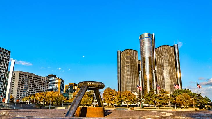 An open plaza with a sculpture in the middle with skyscrapers in the background