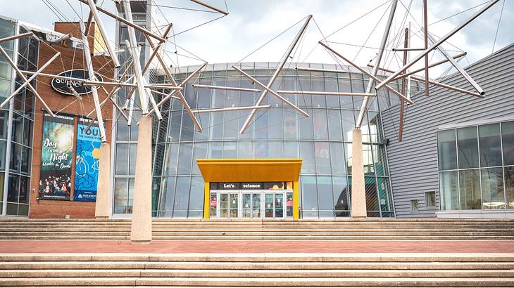 A modern glass building with a metal structure and steps in front of it