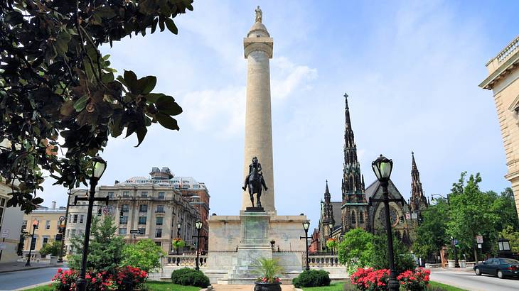 A stone column with a statue atop it and another statue in front of it next to trees