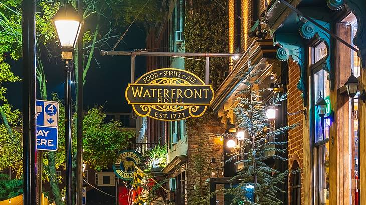 A sign on a brick building that says "Waterfront Hotel" at night