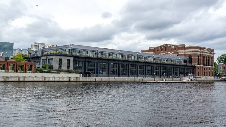 A modern building with red brick walls and glass windows next to a body of water