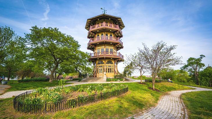 A pagoda-style tower next to green trees, grass, and a walking path