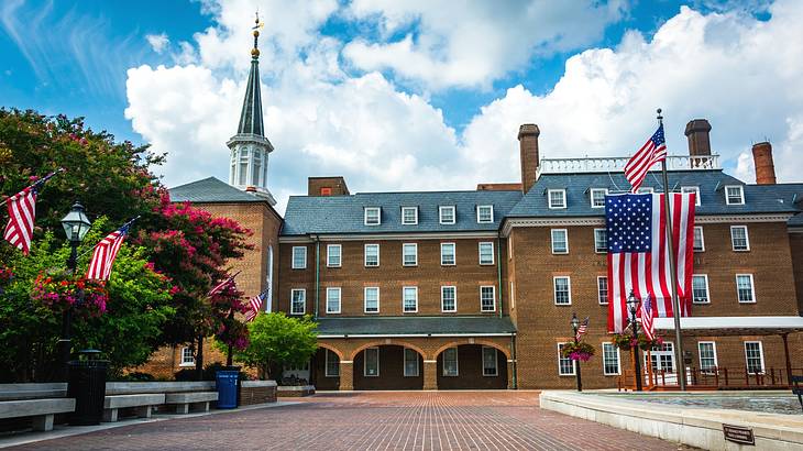 A large red brick building with a tower and a US flag next to a path and trees