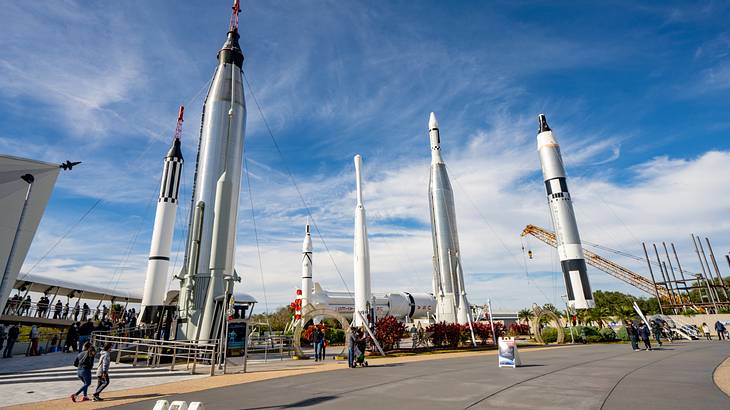 Looking up at white space rocket launchers against a partly cloudy sky