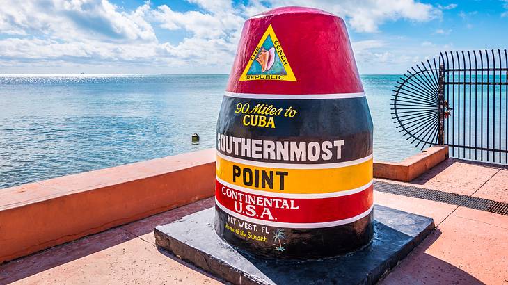 A red-black-yellow buoy with the text "Southernmost Point of The Continental USA"