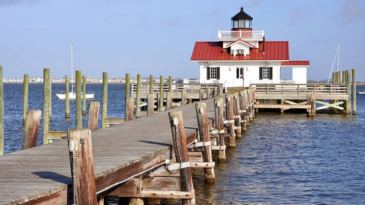 A lighthouse at the end of a pier surrounded by the sea