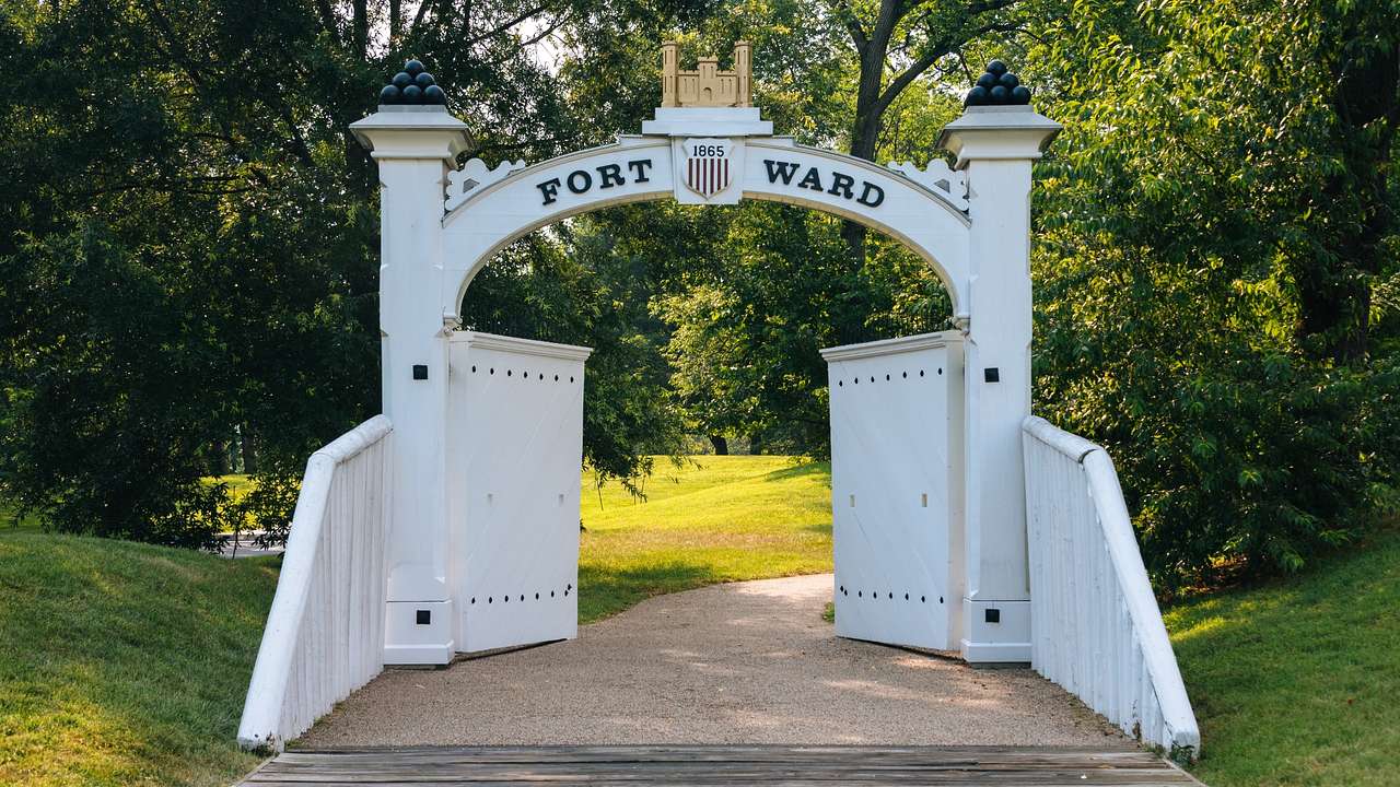 A white arched gate with a sign that says "Fort Ward"