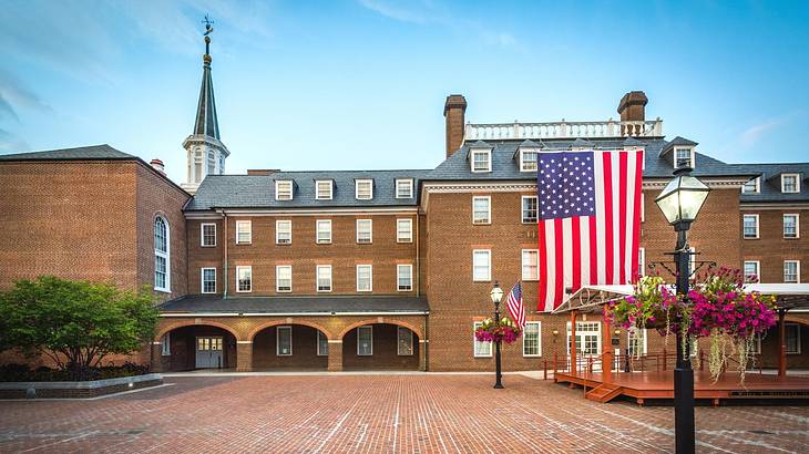 A brick building with an American flag on it sitting in a square under a blue sky