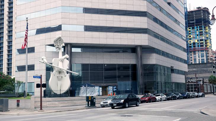 A tall sculpture of a man playing a violin beside a building