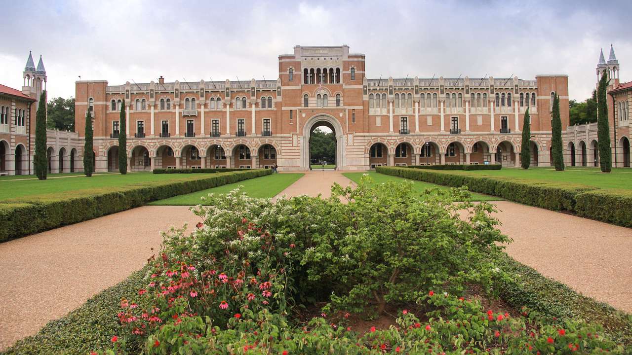 A large building with a walkway and a vast garden in front of it