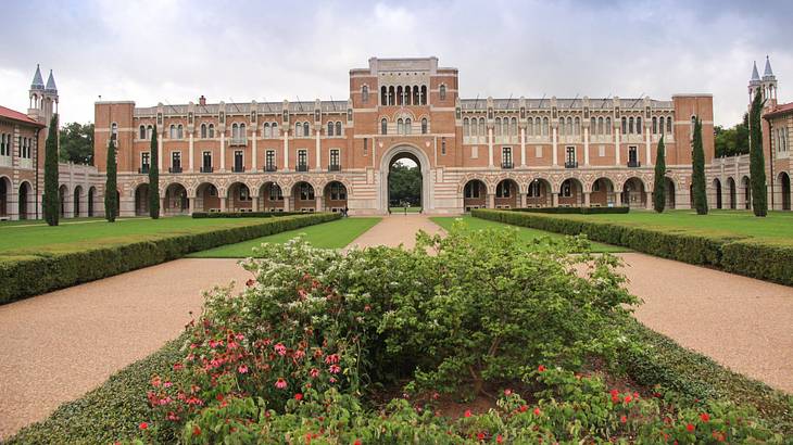 A large building with a walkway and a vast garden in front of it