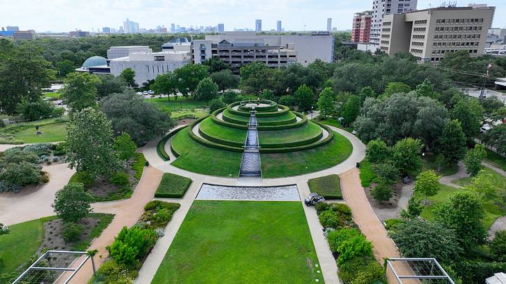 A park with walkways, trees, and a high garden mound in the middle