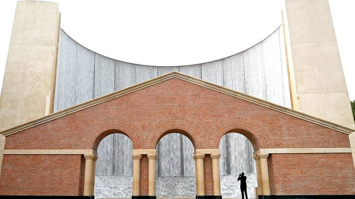 Manmade waterfalls with red brick pillars and archways in front