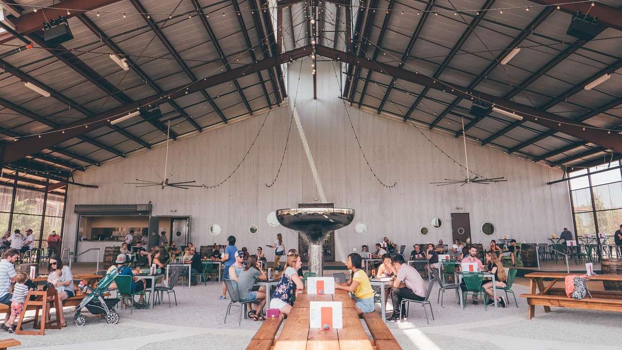 The interior of a bar with a high ceiling and people sitting at tables