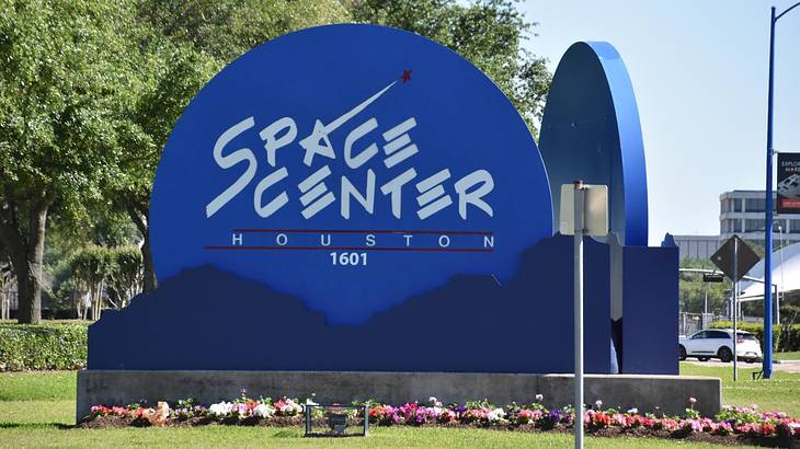 A blue sign on grass that says "Space Center Houston"