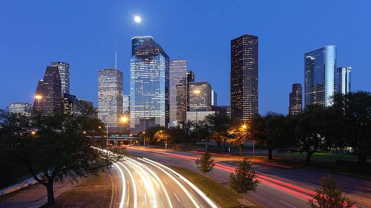 A skyline illuminated at night with a road in front of it