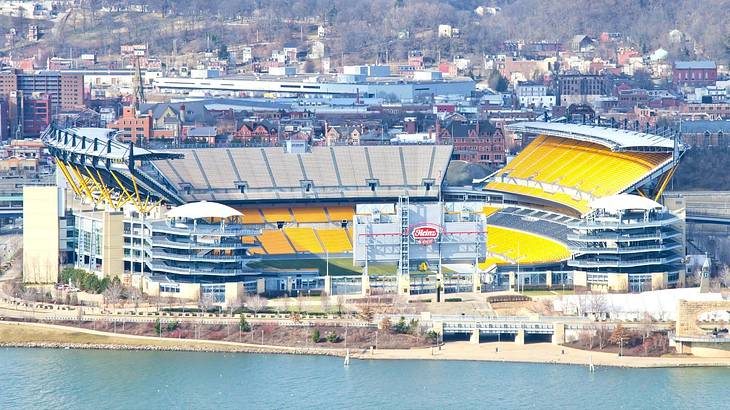 A football stadium with yellow seats and a river in front of it