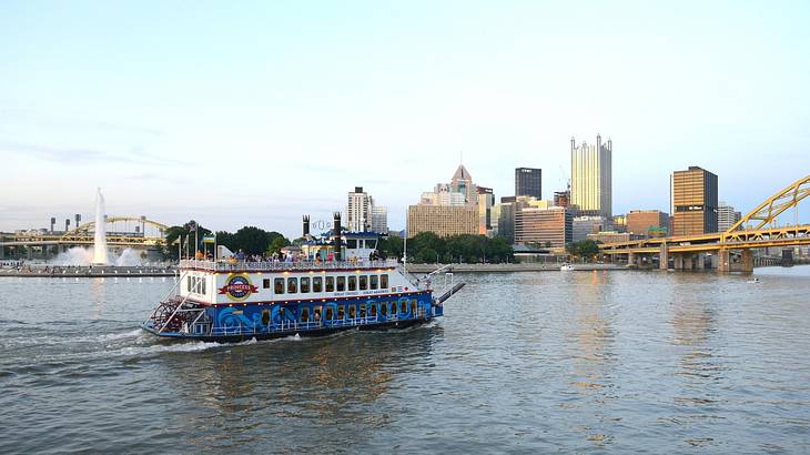 A loaded river barge under the West End bridge on the Ohio river with the  Rivers Casino and Heinz Field in the background in summer time, Pgh, PA, USA  Stock Photo 