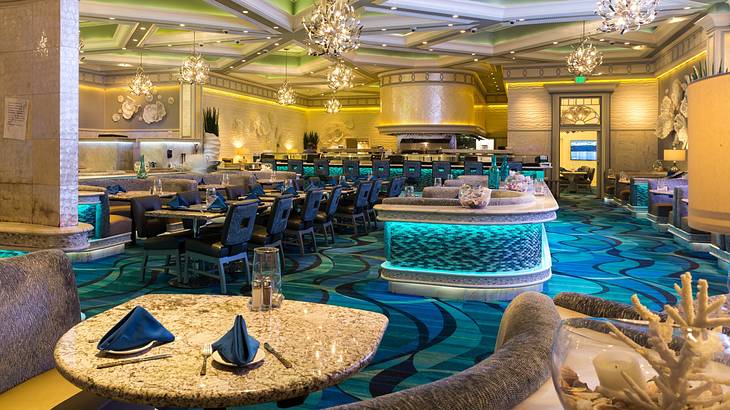 A restaurant dining room with blue carpet and decor and chandeliers