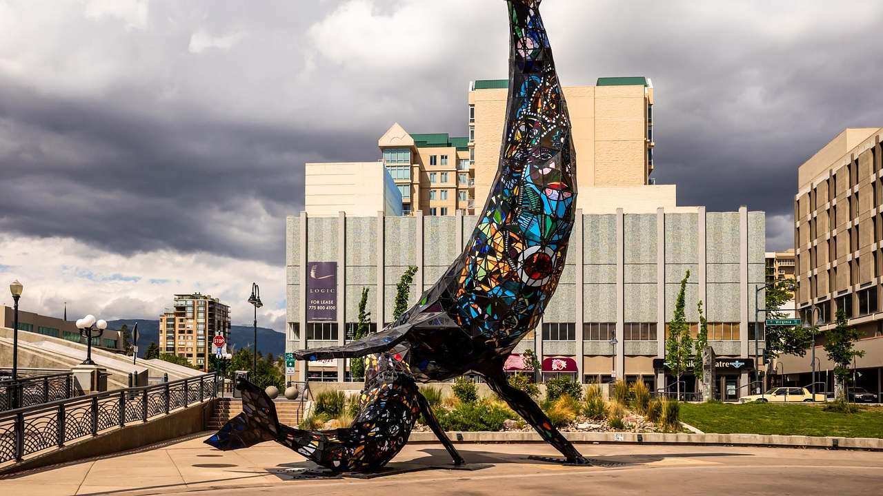 A stained glass statue of a whale and a whale calf in a square under a cloudy sky