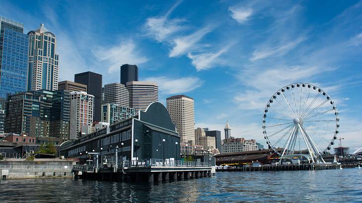 A body of water and a skyline with a Ferris Wheel under a blue sky
