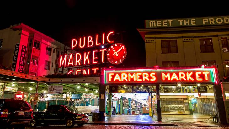 A public market at night with neon red signs and cars parked in front