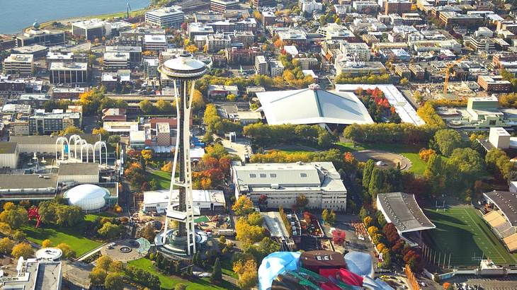 An aerial view of a city with buildings, an observation tower, and greenery