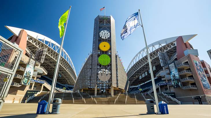 The entrance to a sports arena with flags and a tower