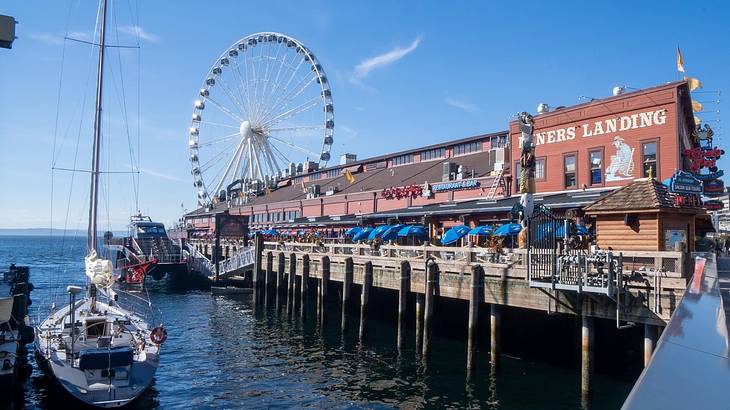 A pier front with a boat in the water, a building, and a Ferris wheel