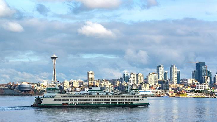 A ferry on the water with a skyline behind it under a cloudy sky