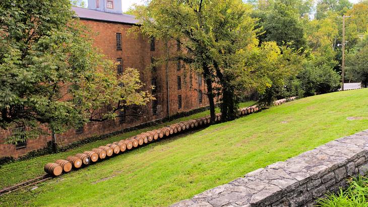 Wooden barrels on a lush hilly terrain near a brick building