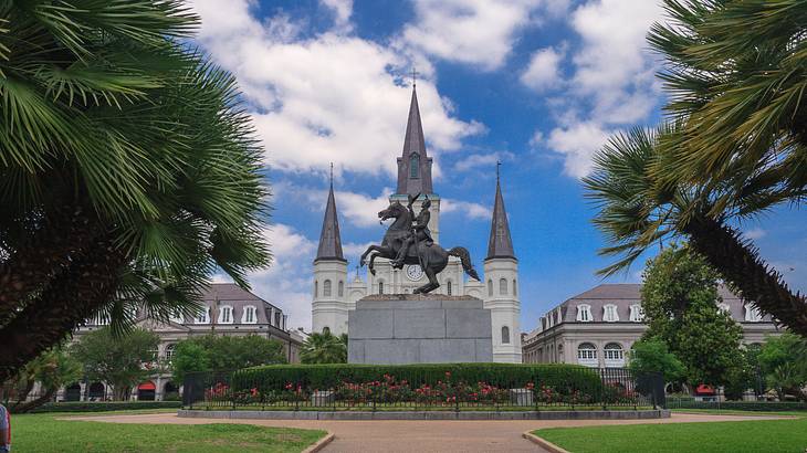 A castle-style cathedral with a statue in front and trees surrounding