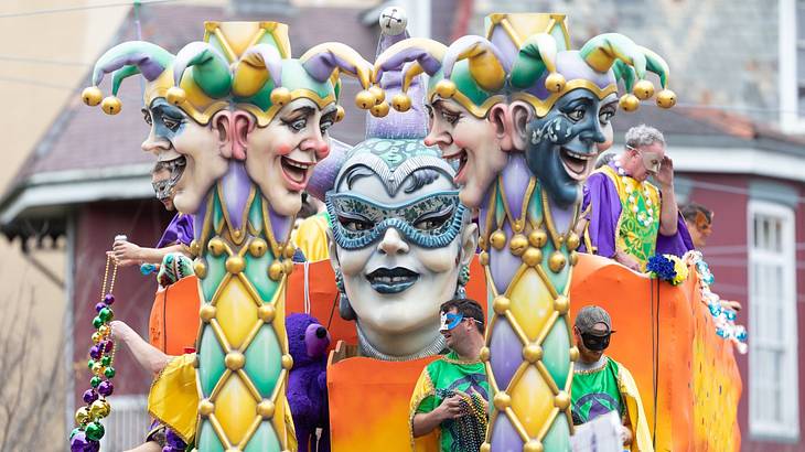 A parade float featuring Jester heads in different colors, with several riders aboard