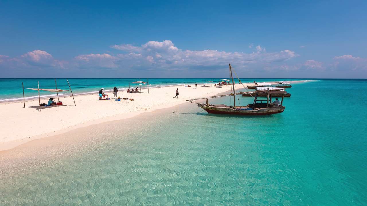 Turquoise water with boats on it next to a white sandbar
