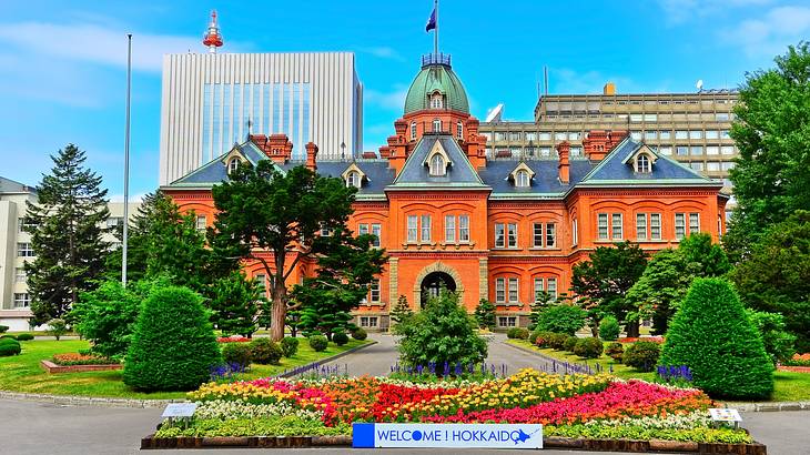 An orange brick building with a garden with blooming flowers in front