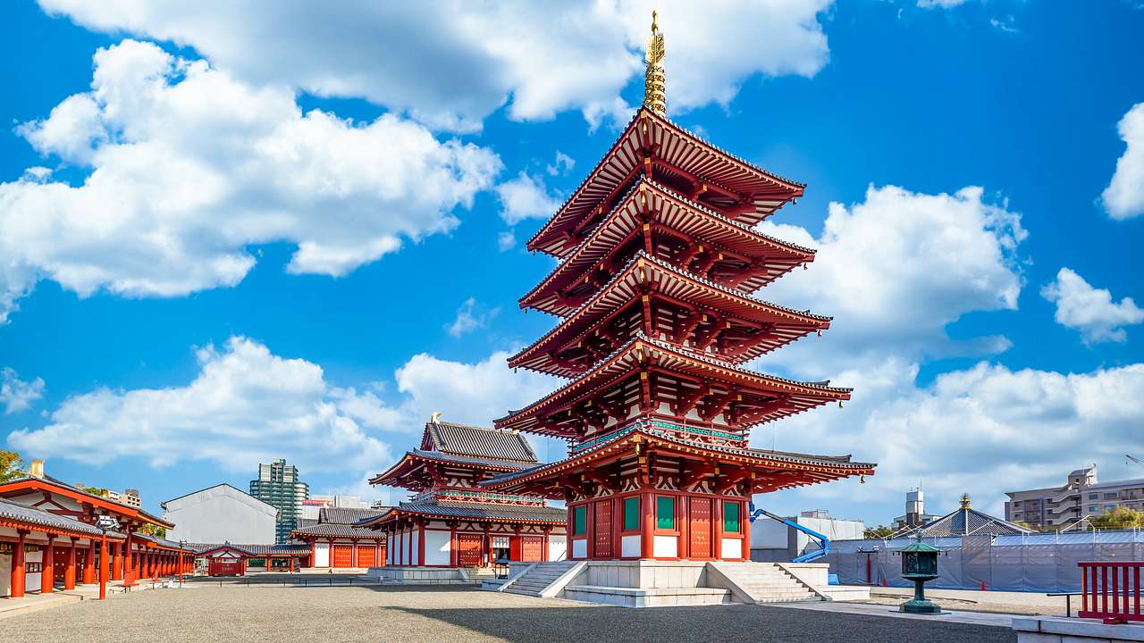 A tall red pagoda surrounded by other small red structures