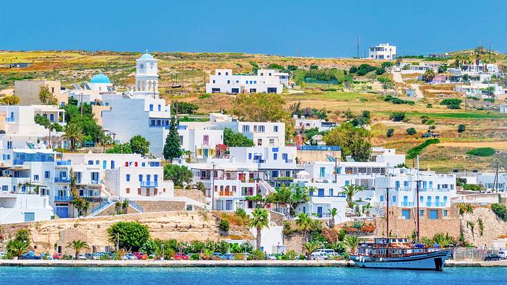 A village of white houses and buildings near a body of water with a ferry