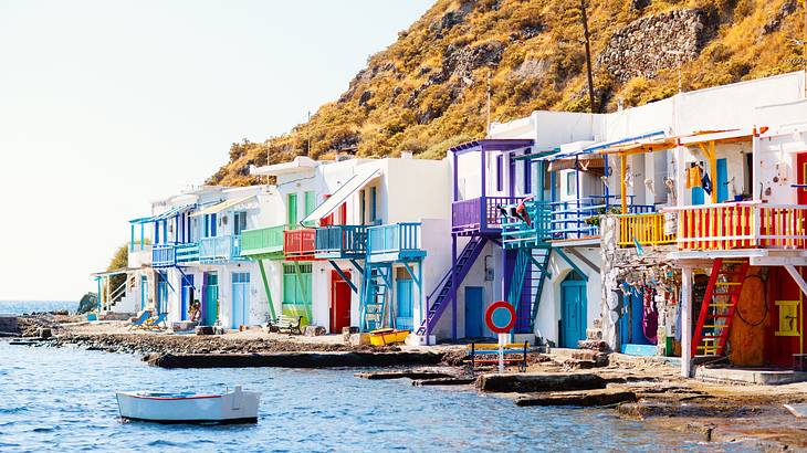 Colorful houses near a mountain and a body of water with a boat