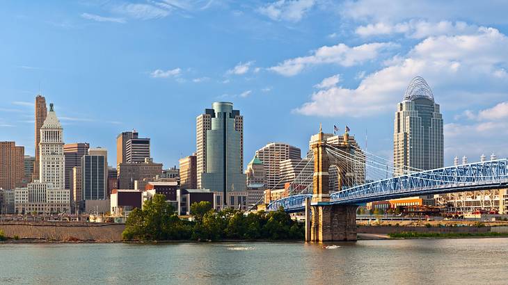 Tall skyscrapers and buildings with a suspension bridge over a body of water in front