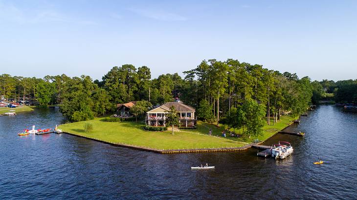 Aerial shot of a house near a forest and a river with small boats