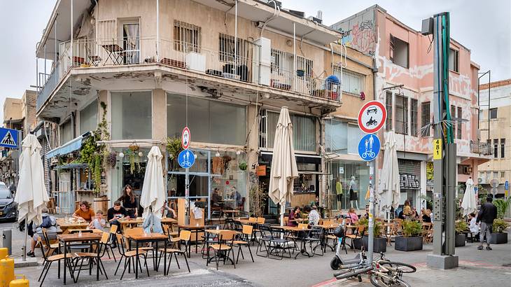 People eating at tables and chairs in front of an old commercial building