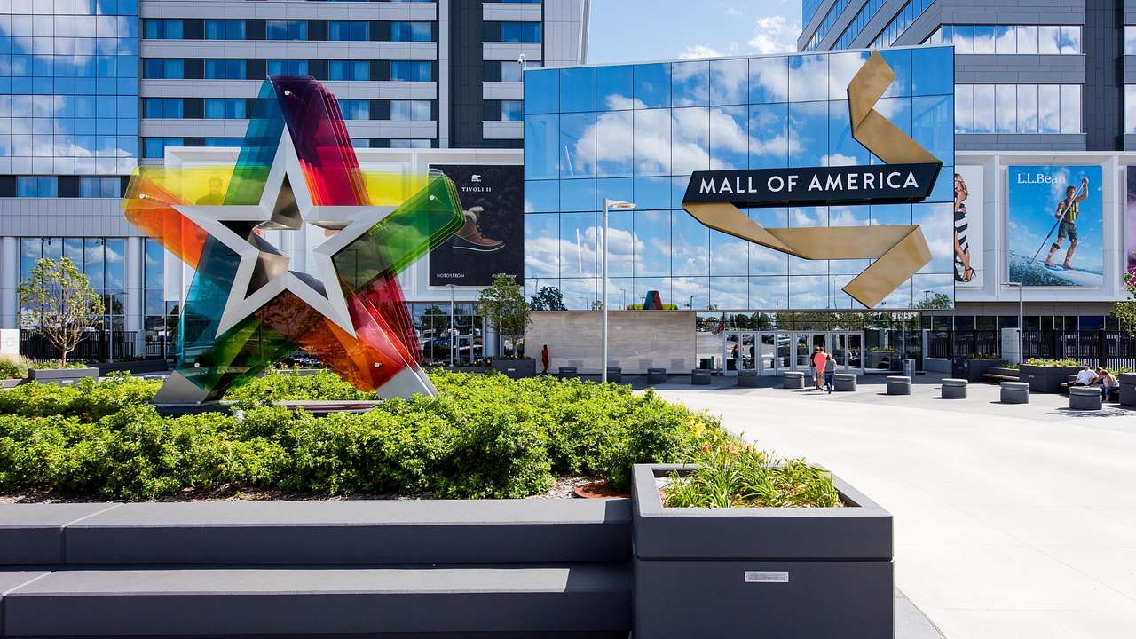 The entry to a mall with greenery, a star sculpture, and a "Mall of America" sign