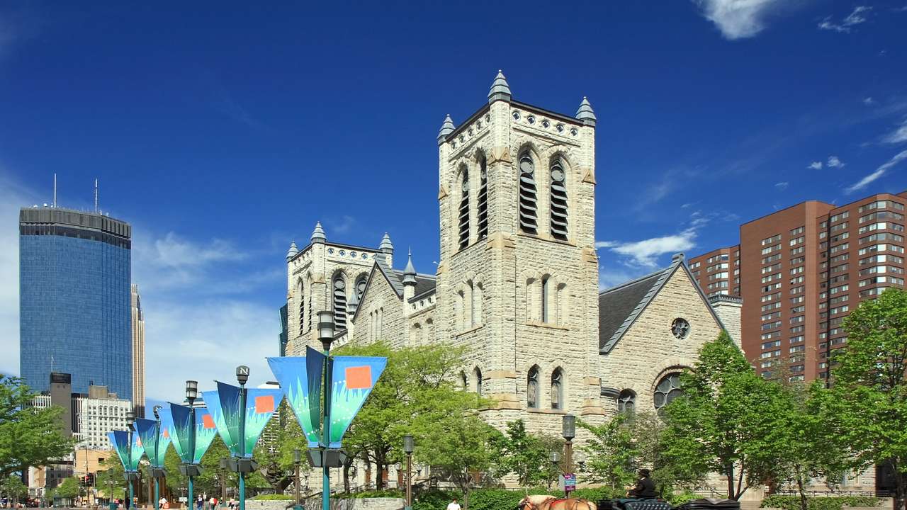 A church with two towers near a walkway with trees and banners