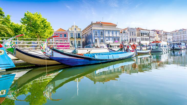 Boats docked by a riverside near trees and colorful structures