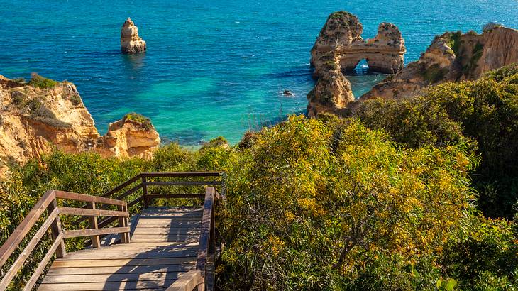 Wooden stairs leading to the shore and the beach near rock formations