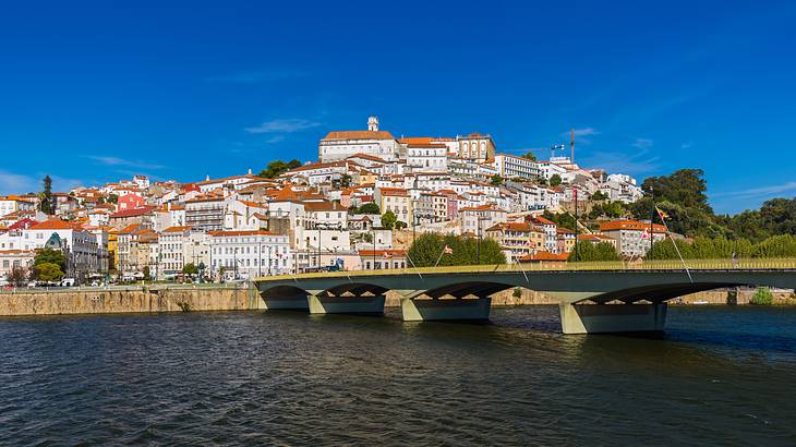 A bridge over a body of water near buildings sitting on a hilly valley