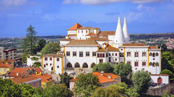 A European Romantic-style castle surrounded by trees under a blue sky