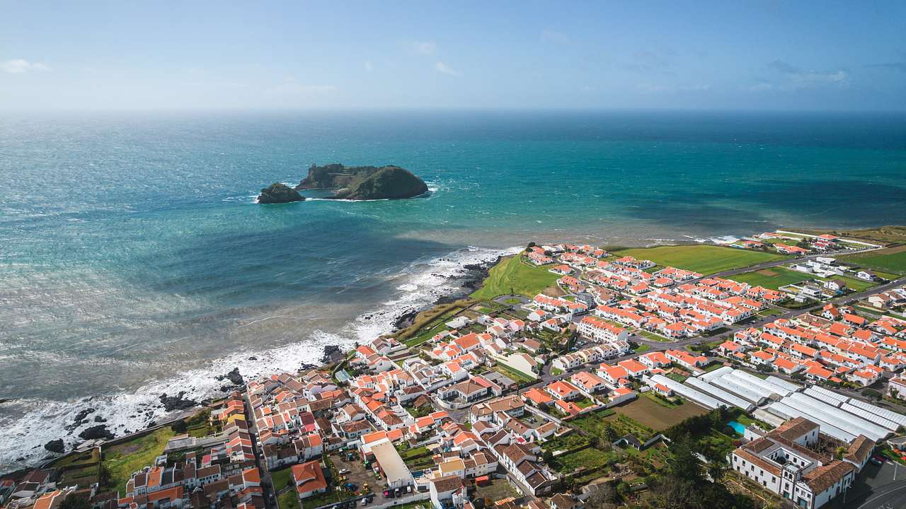 An aerial view of buildings with orange roofs next to the coast