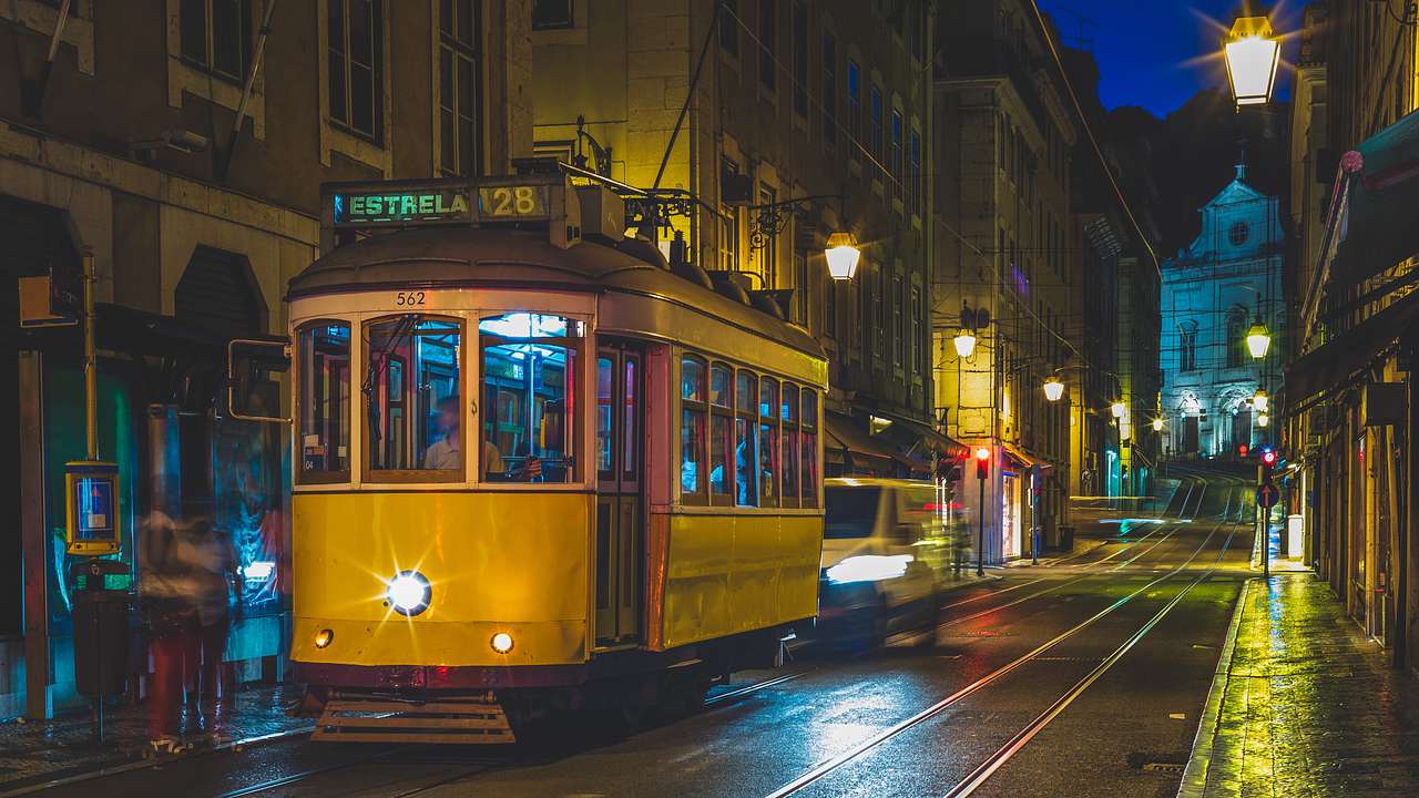 A yellow tram on a track in a city at night