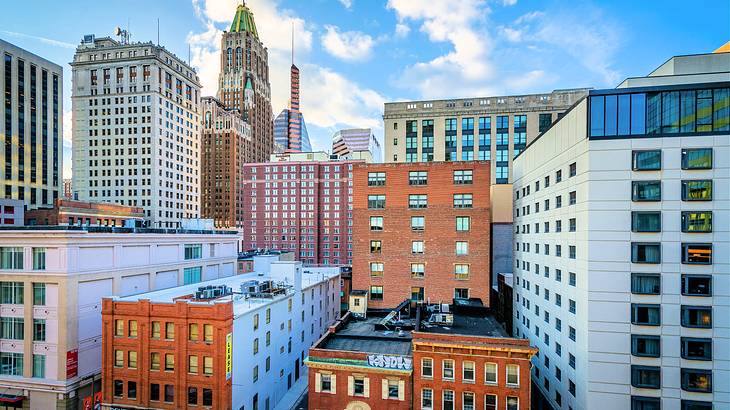 Tall skyscrapers and red brick buildings next to a blue sky with clouds